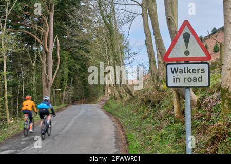 Cyclists on road with Walkers in Road sign on road beside Loweswater, Lake District, Cumbria Stock Photo