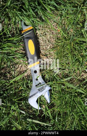 Silver Steel Adjustable Wrench  Spanner in the grass, shot from above Stock Photo