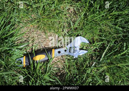 Silver Steel Adjustable Wrench  Spanner in the grass, shot from above Stock Photo