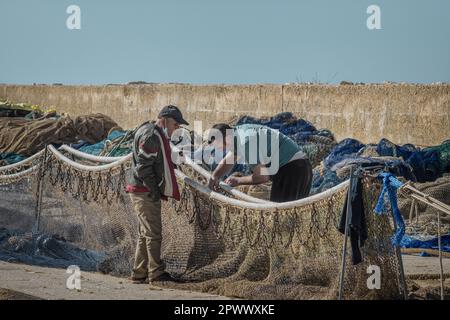 Fisherman and his father with a bandaged hand mending nets in the fishing port of the town of Altea in the province of Alicante, Spain, Europe Stock Photo
