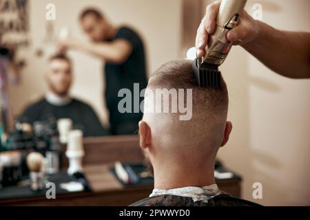 Rear view of master hairdresser does hairstyle with scissors and comb. Stock Photo