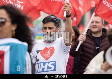 London, UK. 01st May, 2023. An NHS pharmacist from Unite the Union holds a flag while marching during the demonstration on the Labour Day. Nursing members from the Royal College of Nursing (RCN) and other NHS workers from the Unite Union marched from St Thomas's Hospital to Trafalgar Square on the Labour Day to join other workers demanding a proper pay rise and improvement in working conditions from the UK government. Credit: SOPA Images Limited/Alamy Live News Stock Photo