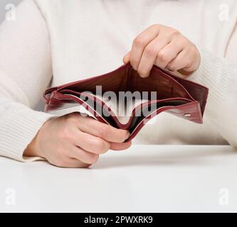 Two female hands hold an empty brown leather wallet, poverty Stock Photo