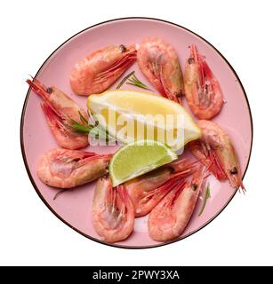 Boiled shrimp, lemon and lime slices, spices in a round pink plate on a white isolated background Stock Photo