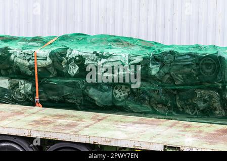 Container with engines and pressed cars piled up as scrap metal for recycling Stock Photo