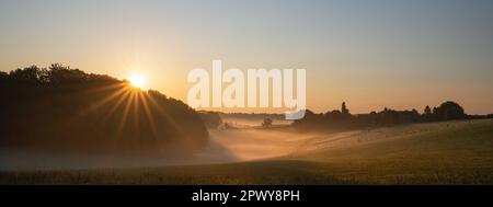 Panoramic landscape image of sunrise on a foggy morning during autumn, Bergisches Land, Germany Stock Photo