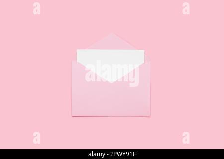 Closeup on blank empty white paper card in pink opened envelope isolated on pink pastel color background. Love letter minimal concept. Conceptual layo Stock Photo