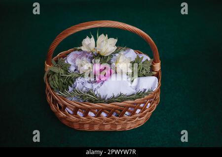 Easter basket on turquoise background, decorated with flowers and containing Easter foods, ready to be brought to church for easter blessing Stock Photo
