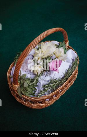 Easter basket on turquoise background, decorated with flowers and containing Easter foods, ready to be brought to church for easter blessing Stock Photo
