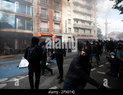 Demonstrators and French Police clash during the Mayday riots on 1st May 2023 in the centre of Paris. Many people turned up to express their dislike of President Macron and his current policies. Picture of rioter throwing projectile at police. Stock Photo