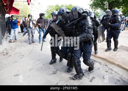 Demonstrators and French Police clash during the Mayday riots on 1st May 2023 in the centre of Paris. Many people turned up to express their dislike of President Macron and his current policies. Picture of injured French Riot Police Officer being helped by two other officers. Stock Photo