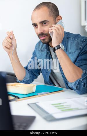 male architect sat at desk talking on the telephone Stock Photo