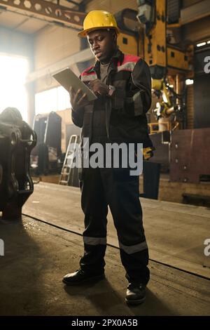 Young African American male technician looking through online manual while standing in front of camera and preparing for machine repair Stock Photo