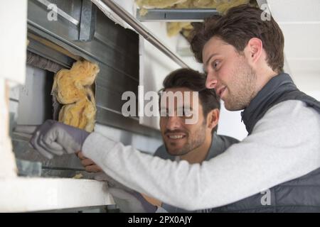 two men working with foiled insulation on the window sill Stock Photo