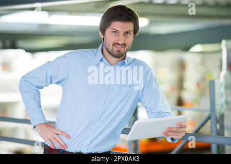 portrait of smiling factory worker using a tablet in factory Stock Photo