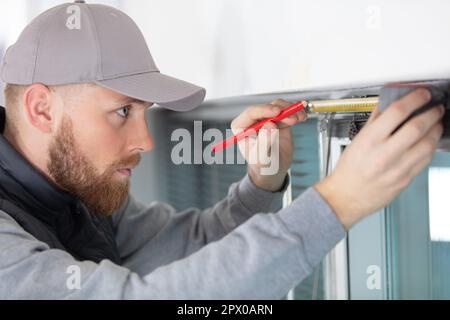 service man installing window with measure tape Stock Photo