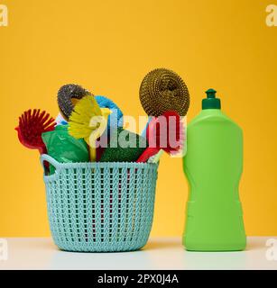 Plastic basket with brushes, disinfectant in a bottle on a yellow background Stock Photo