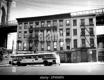 AJAXNETPHOTO. JULY, 1975. BROOKLYN, NEW YORK, USA. - OLD CADMAN PLAZA WEST - BROOKLYN BRIDGE TOWER (LEFT)  EMERGING BEHIND NINETEENTH CENTURY (1890S) COMMERCIAL BUILDINGS ON CADMAN PLAZA WEST; THE DECK OF THE BROOKLYN BRIDGE SPANNING EAST RIVER BETWEEN PARK ROW MANHATTAN AND SANDS STREET, BROOKLYN, NEW YORK CiTY. CAN BE SEEN BEHIND. VIEW NOW (2023) OBSCURED BY TREES AND STREET RENAMED OLD FULTON. PHOTO:JONATHAN EASTLAND/AJAXREF:232404 118 Stock Photo