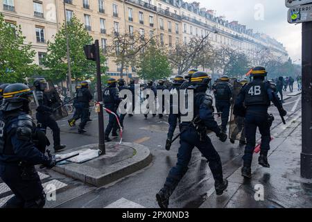 French CRS riot police charging violent protesters with batons during a demonstration against the government's retirement reform in a street of Paris