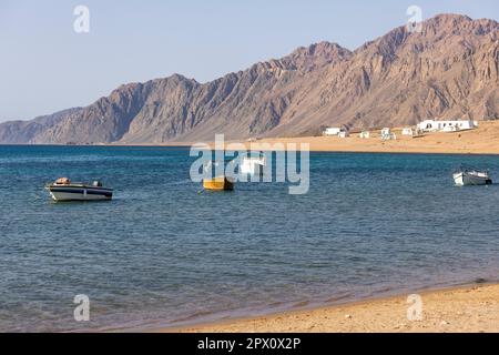 View of Red Sea and boats moored in the port, Dahab, Egypt. Dahad is a former Bedouin village surrounded by mountains, now one of the most valuable di Stock Photo
