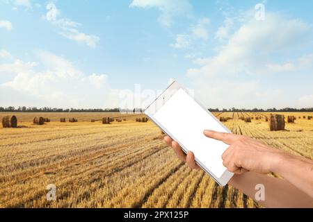 Farmer with tablet computer in harvested wheat field. Banner for design Stock Photo