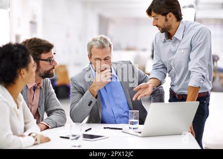 Leading his team through the creative process. a group of a diverse group of business professionals having a meeting. Stock Photo