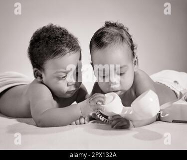 1960s TWO AFRICAN-AMERICAN BABY BOYS PLAYING WITH TELEPHONE - n2347 HAR001 HARS AFRICAN-AMERICANS AFRICAN-AMERICAN BLACK ETHNICITY PHONES TELEPHONES BABY BOY COOPERATION GROWTH JUVENILES BLACK AND WHITE CURIOSITY HAR001 OLD FASHIONED AFRICAN AMERICANS Stock Photo