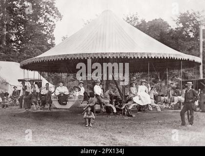 1890s MEN WOMEN AND CHILDREN POSED ON MERRY-GO-ROUND IN SHELTON GROVE IN 1894 - o2817 HAR001 HARS HALF-LENGTH LADIES PERSONS INSPIRATION MALES CARNIVAL ENTERTAINMENT B&W EYE CONTACT AMUSEMENT HAPPINESS ADVENTURE LEISURE TURN OF THE 20TH CENTURY AND RIDERS EXCITEMENT LOW ANGLE RECREATION CAROUSEL INNOVATION MERRY-GO-ROUND AMUSEMENT RIDE COOPERATION GROWTH JUVENILES POSED RIDES 1894 AMUSEMENT PARK BLACK AND WHITE CAUCASIAN ETHNICITY GROVE HAR001 OLD FASHIONED Stock Photo