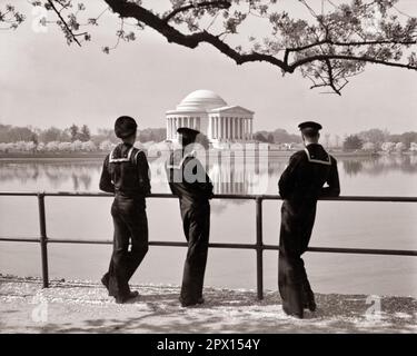 1940s THREE US NAVY SAILORS IN DRESS BLUES LOOKING AT JEFFERSON MEMORIAL DURING CHERRY BLOSSOMS FESTIVAL WASHINGTON DC USA - q75051 CPC001 HARS PEACE TEAMWORK JOY CONFLICT SAILOR WW2 NAVY UNITED STATES COPY SPACE FRIENDSHIP FULL-LENGTH PERSONS UNITED STATES OF AMERICA FESTIVAL MALES FORCE B&W NORTH AMERICA FREEDOM NORTH AMERICAN DREAMS ADVENTURE CHERRY GLOBAL NAVAL DISTRICT OF COLUMBIA EXCITEMENT WORLD WARS PRIDE WORLD WAR WORLD WAR TWO REAR VIEW WORLD WAR II AT ON OCCUPATIONS SAILORS UNIFORMS CAPITAL FORCES FROM BEHIND NAVIES WORLD WAR 2 USN BACK VIEW BLOSSOMS BLUES TOGETHERNESS Stock Photo