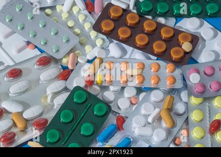 A large pile of pills in bundles scattered on the table. A mound of multi-colored tablets and blister packs. Close-up, copy space Stock Photo
