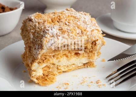 A piece of Napoleon cake on a plate. Sweet delicious dessert of puff pastry with custard. Stock Photo