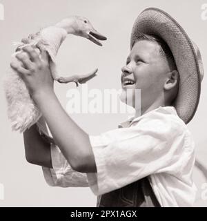 1920s 1930s FARM BOY WEARING STRAW HAT AND OVERALLS SITTING ON LOG WITH  SPOTTED DOG FISHING IN POND - a4779c HAR001 HARS NOSTALGIA OLD FASHION 1  JUVENILE POLE FRIEND POND TEAMWORK HOLE