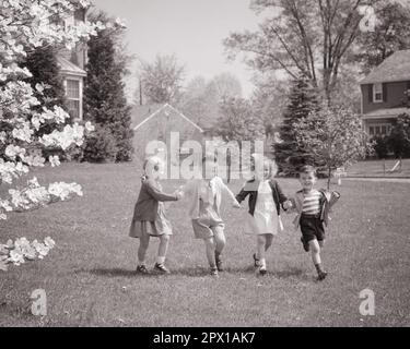 1940s 1950s TWO BOYS TWO GIRLS BROTHERS AND SISTERS RUNNING TOGETHER HOLDING HANDS IN SPRINGTIME ON FRONT LAWN OF SUBURBAN HOME - j1314 HAR001 HARS JUVENILE YARD STYLE LAUGH TEAMWORK PLEASED JOY LIFESTYLE SATISFACTION FEMALES EASTER BROTHERS HEALTHINESS HOME LIFE COPY SPACE FRIENDSHIP FULL-LENGTH MALES SIBLINGS SISTERS B&W NEIGHBORS FREEDOM HAPPINESS NEIGHBORHOOD CHEERFUL ADVENTURE LEISURE BLOSSOM AND EXCITEMENT RECREATION SIBLING SMILES SWEATERS CONNECTION JOYFUL STYLISH SUPPORT FANCY DRESS COOPERATION GROWTH JUVENILES SPRING SEASON SPRINGTIME TOGETHERNESS BLACK AND WHITE CAUCASIAN ETHNICITY Stock Photo
