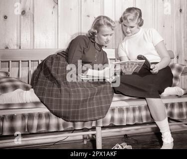 1950s TWO BLOND TEENAGE GIRLS SISTERS SITTING TOGETHER READING FASHION MAGAZINES - j7024 HAR001 HARS FEMALES HOME LIFE COPY SPACE FRIENDSHIP HALF-LENGTH PERSONS INSPIRATION TEENAGE GIRL SIBLINGS SISTERS B&W SKIRTS DREAMS HAPPINESS LEISURE LOW ANGLE MAGAZINES SIBLING FRIENDLY GIRLFRIENDS STYLISH KNOTTY PINE COOPERATION JUVENILES PANELING RELAXATION TOGETHERNESS BFF BLACK AND WHITE BOBBY SOCKS CAUCASIAN ETHNICITY HAR001 NO SHOES OLD FASHIONED Stock Photo