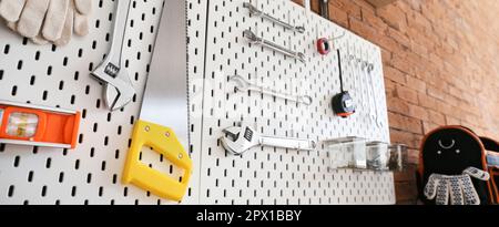 Pegboards with tools hanging on brick wall in workshop Stock Photo