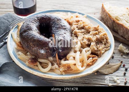 Bloody sausage morcilla, stewed sour turnip and mashed potato with brown beans close up. Traditional Slovenian dish with roasted bloody sausage Stock Photo