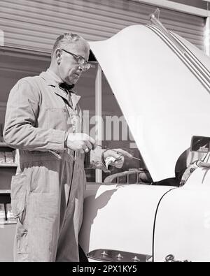 1950s MAN GAS STATION ATTENDANT CHECKING LEVEL OF OIL IN AUTOMOBILE ENGINE - m5124 HAR001 HARS PERSONS OVERALLS AUTOMOBILE MALES PROFESSION TRANSPORTATION MIDDLE-AGED B&W GOALS SKILL OCCUPATION SKILLS MIDDLE-AGED WOMAN DISCOVERY PROTECTION CUSTOMER SERVICE AUTOS CAREERS LOW ANGLE LABOR OPPORTUNITY EMPLOYMENT OCCUPATIONS MAINTENANCE AUTOMOBILES INSPECTING VEHICLES INFRASTRUCTURE OILS EMPLOYEE ATTENDANT DIPSTICK LEVEL LUBRICATION BLACK AND WHITE CAUCASIAN ETHNICITY COVERALLS FOSSIL FUEL HAR001 LABORING OLD FASHIONED Stock Photo