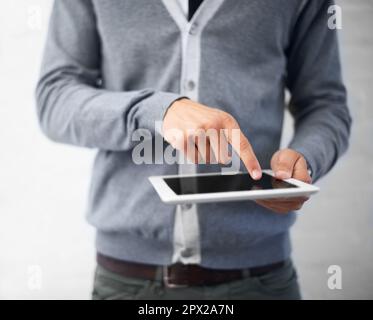 Checking his emails on the go. Cropped image of a young man working on his digital tablet. Stock Photo