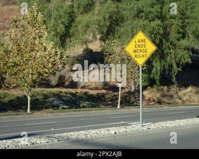 Yellow Left Lane Ends Merge Right Sign on center divider. Stock Photo