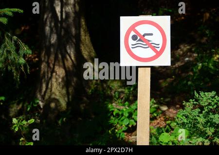 A pillar with a sign denoting a ban on swimming. The sign shows a crossed-out floating person Stock Photo