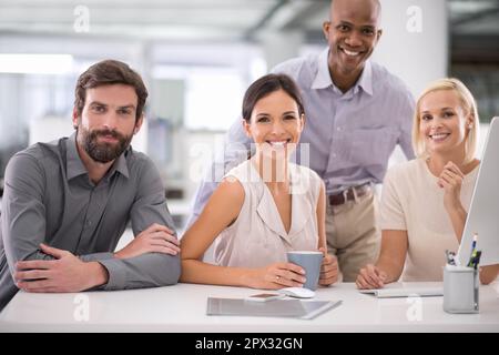 Focused on the future. a group of smiling businesspeople gathered at their desk. Stock Photo