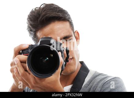 Hes got an eye for photography. Portrait of a young man holding a camera and taking pictures against a white background. Stock Photo