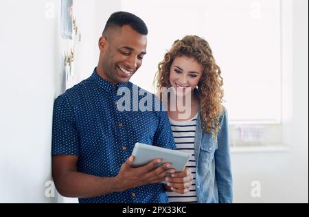 Well get any job done...together. two young colleagues using a digital tablet. Stock Photo