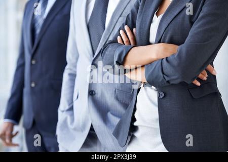 Corporate colleagues. Closeup cropped image of a businesswoman standing with her arms crossed with two colleagues next to her. Stock Photo