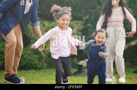 Play is our brains favourite way of learning. two adorable little girls having fun with their family outdoors Stock Photo