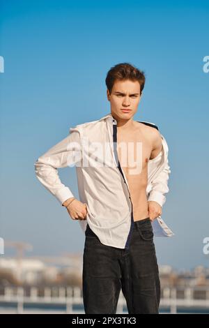 Young man in unfastened white shirt on the street Stock Photo