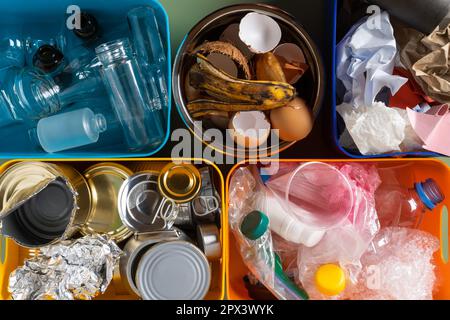 Multicolored plastic containers filling with different sort of waste and rubbish, like organic food, paper, plastic, can, tin, metal things. Environme Stock Photo