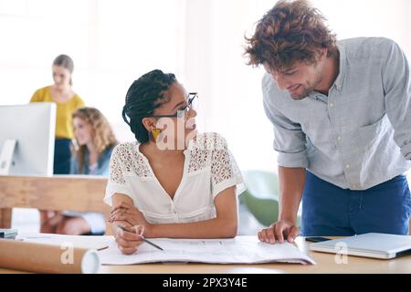 Working together for better results. two young designers working together in their office. Stock Photo