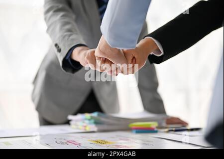 Close-up image of diverse businesspeople bumping their fists together over a table during the meeting. Teamwork, cheer up, Unity, Motivation Stock Photo