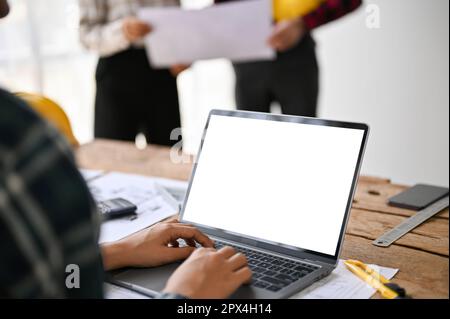 Close-up image of a female architect or engineer using a laptop computer in the office. laptop white screen mockup for display your graphic ads Stock Photo